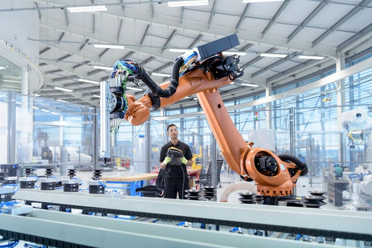 Künstliche Intelligenz und Recht: Ein Industrieroboter wird von einem Menschen programmiert.