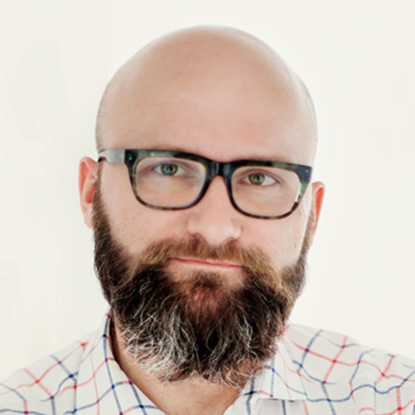 Dr. hab. Tomasz Piekot, der ein kariertes Hemd trägt, lehnt mit verschränkten Armen gegen eine Wand.