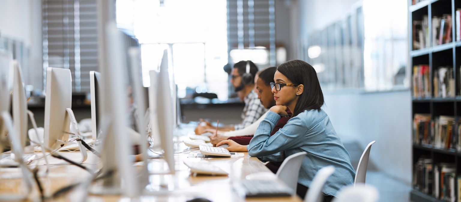 Einkommensabhängige Kredite: Studenten sitzen in der Bibliothek vor Computern.