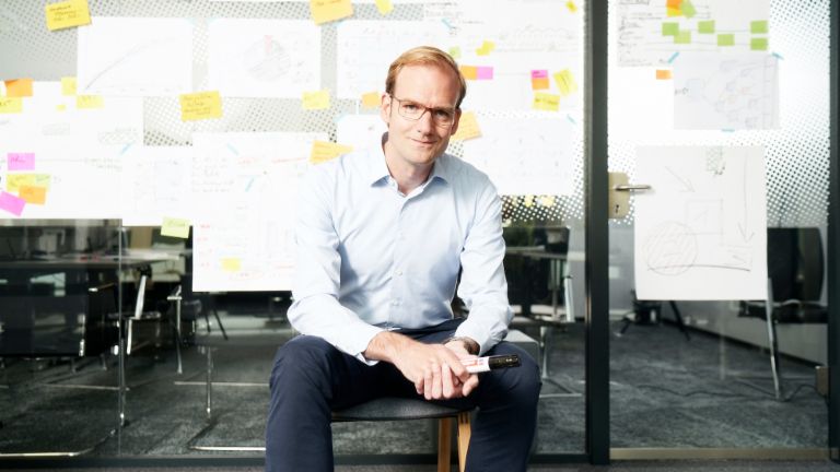 Forderungskauf: Matthias Schmidt, Leiter Operativer Forderungskauf der EOS Gruppe, sitzt vor einer mit Zettel beklebten Wand.