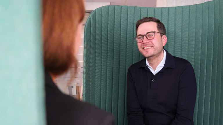 Ein Mann in einer Büroumgebung in einer Interviewsituation.