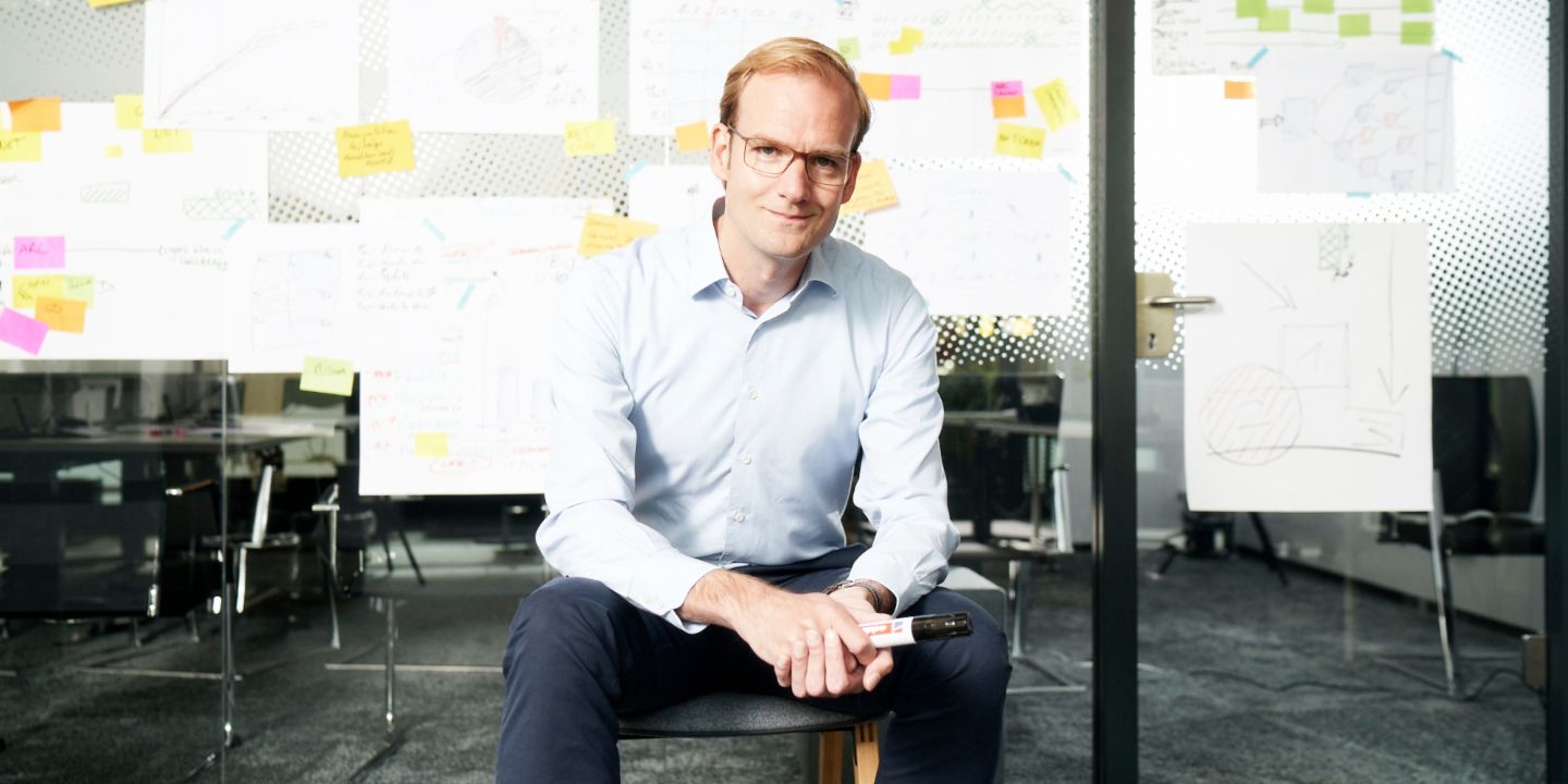 Forderungskauf: Matthias Schmidt, Leiter Operativer Forderungskauf der EOS Gruppe, sitzt vor einer mit Zettel beklebten Wand.