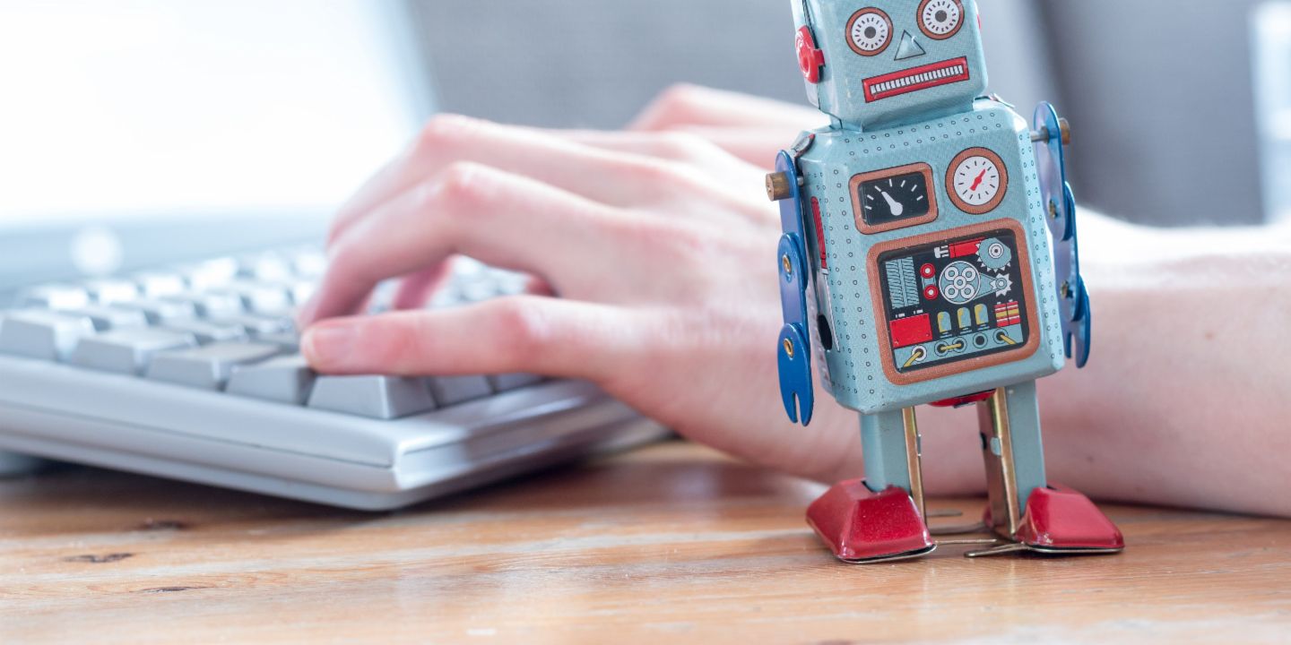 Robotic Process Automation: eine Roboterfigur vor einem Computer.
