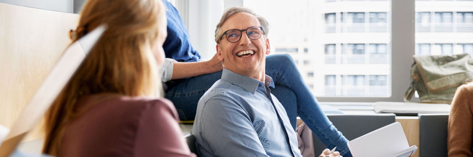 EOS Mitarbeitende sitzen in einem modernen Büro und führen eine Besprechung, während sie Notizen machen.
