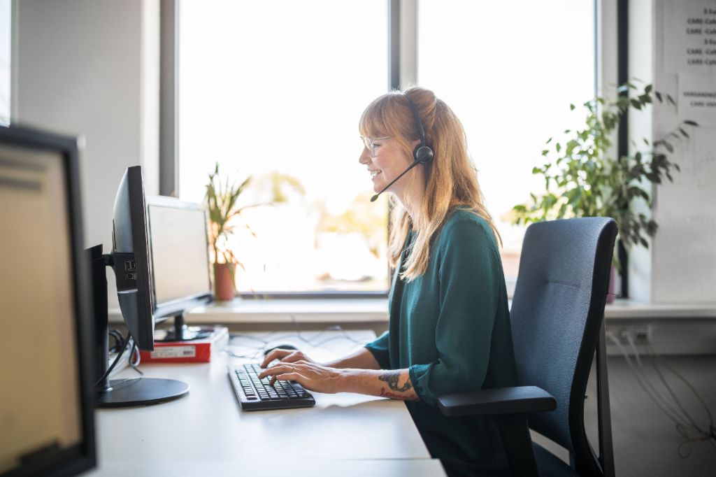 Eine junge Frau mit Headset arbeitet am Computer