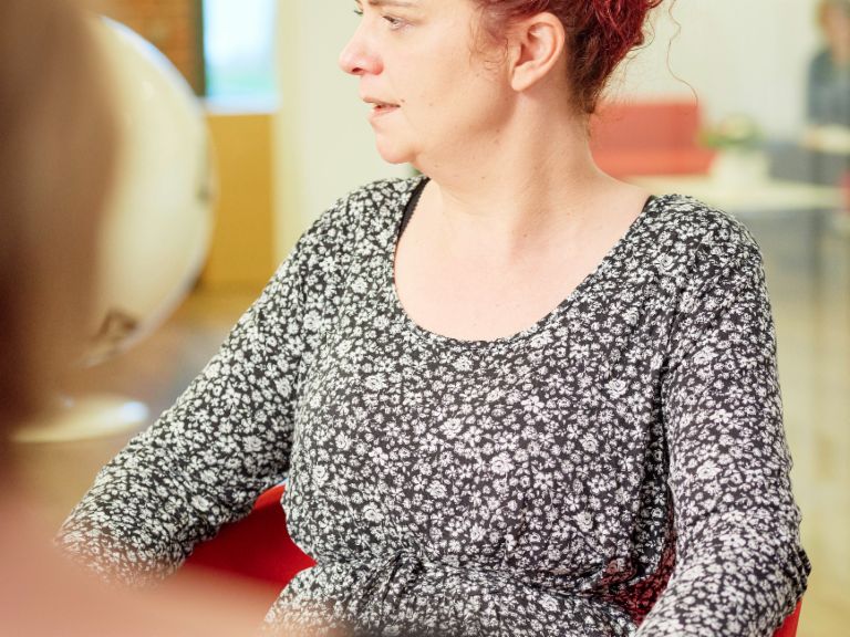 Interview: Call Center Agentin Katja Wolf sitzt in einem Sessel.