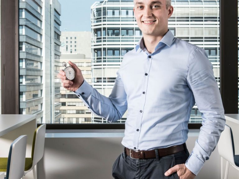 Datentraining: Ein Mann steht im Büro und hält eine Stoppuhr.