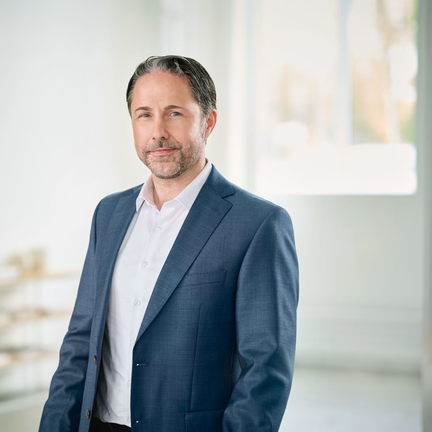 Portrait von Marwin Ramcke, Vorsitzender der Geschäftsführung der EOS Gruppe in einem hellen Raum und trägt ein dunkles Sakko