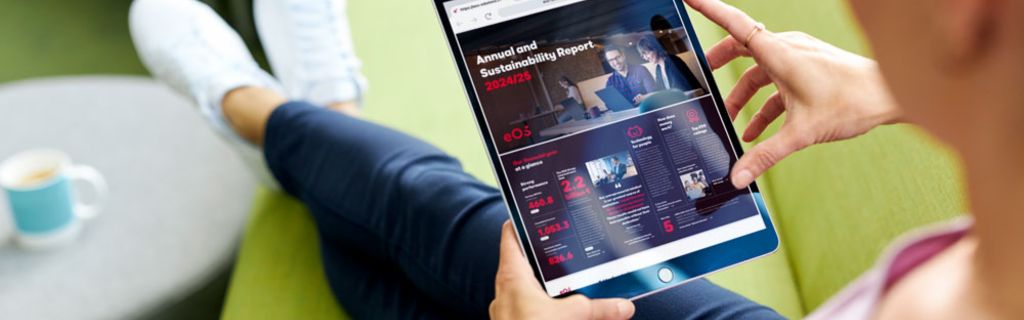 Person auf grünem Sofa, die den EOS Jahres- und Nachhaltigkeitsbericht 2024/25 auf einem Tablet betrachtet