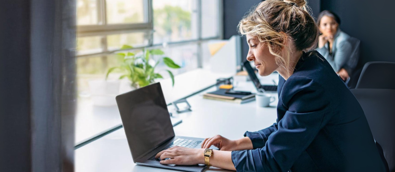 Junge Frau arbeitet an einem Laptop in einem modernen Büro.