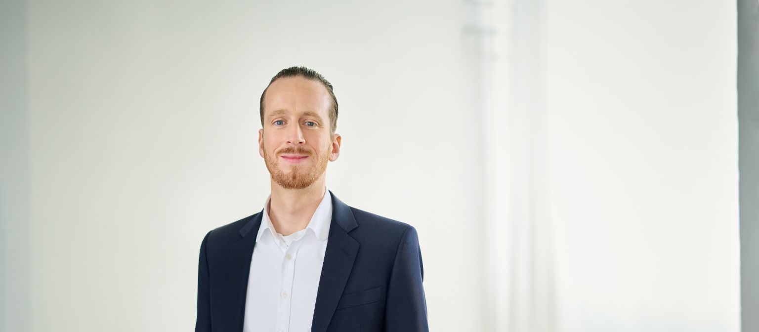 Sebastian Pollmer in a suit standing in a bright room