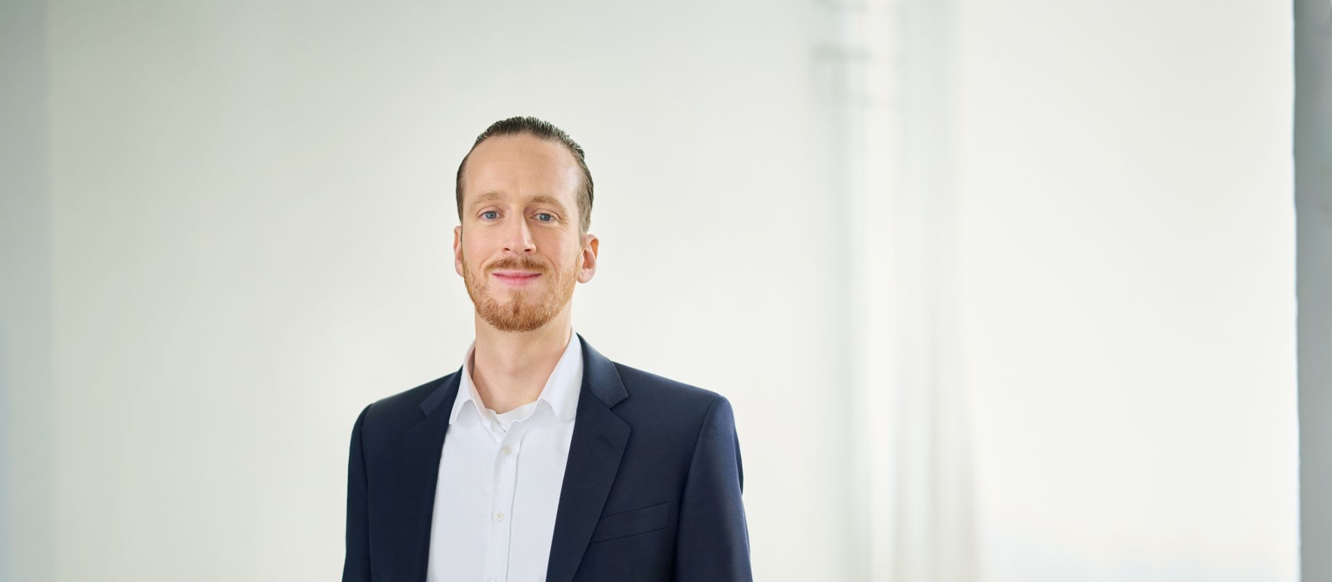 Sebastian Pollmer in a suit standing in a bright room