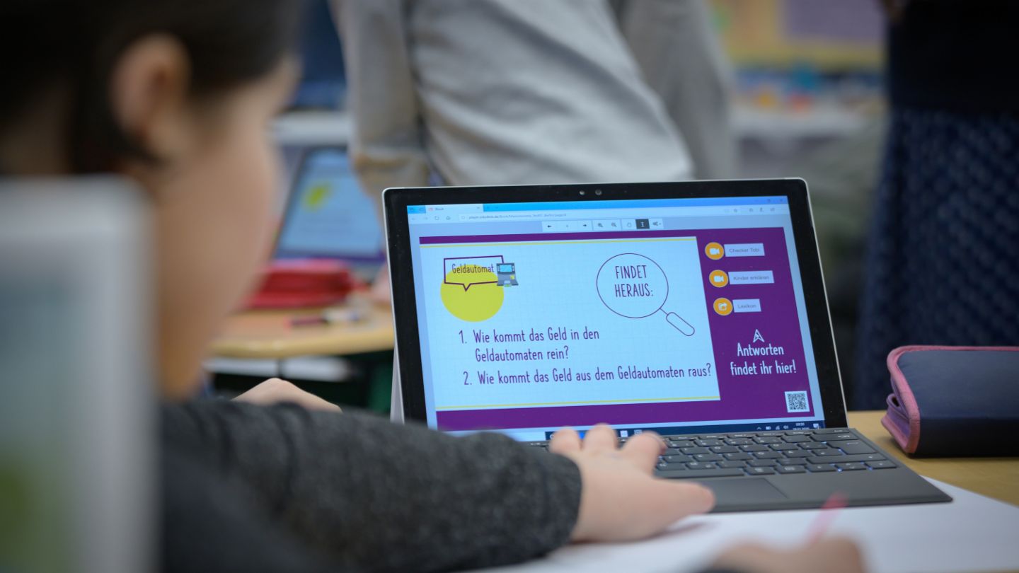 Finanzbildung für Kinder: Kind sitzt am Laptop und lernt etwas über Finanzen.