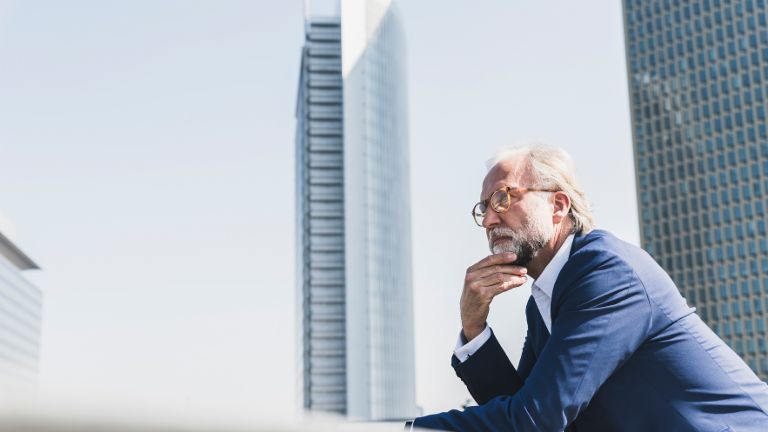 Inkasso beauftragen: Geschäftsmann steht nachdenklich inmitten einer Geschäftsmetropole.