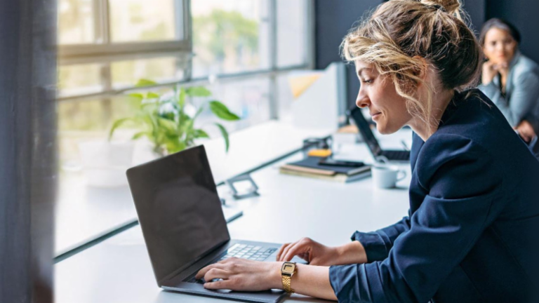 Junge Frau arbeitet an einem Laptop in einem modernen Büro.