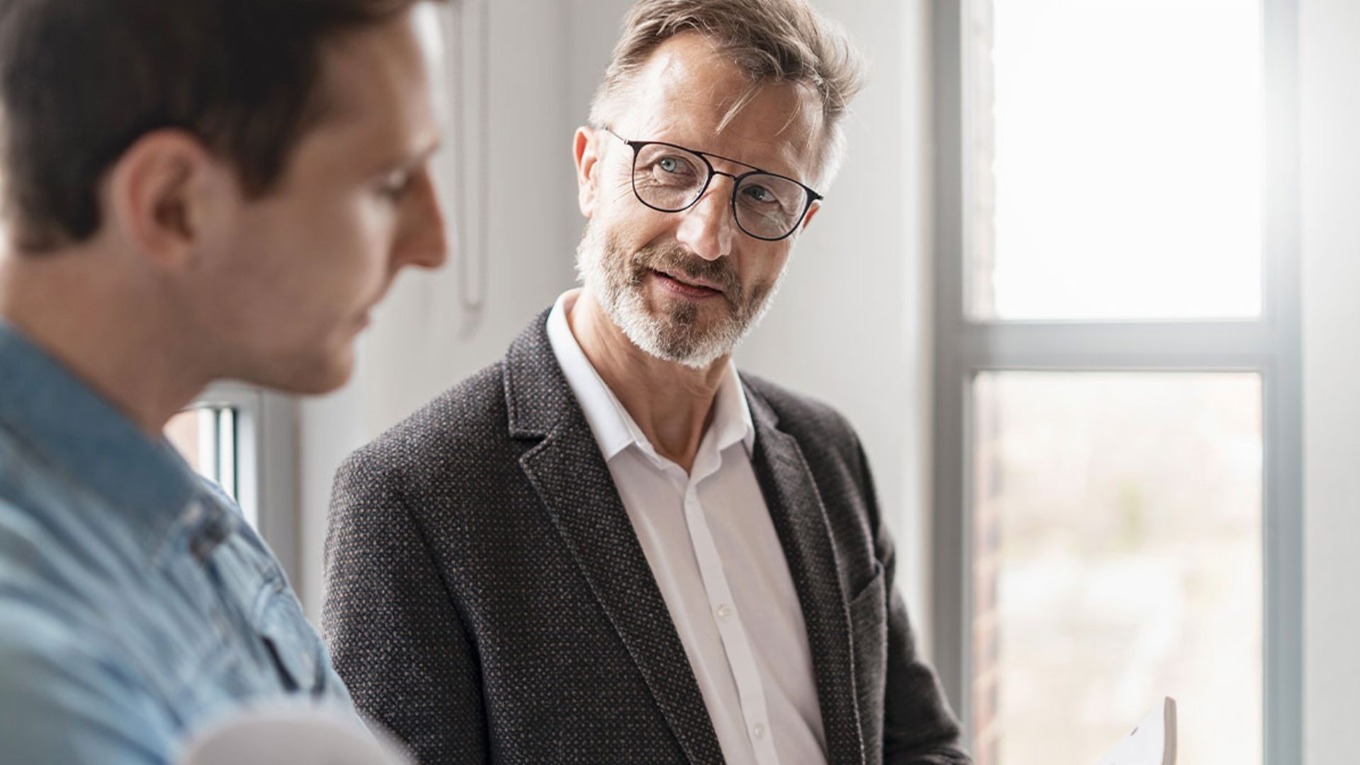 Zwei Männer im Büro sprechen über die Ergebnisse der Studie European Payment Practices 2025 der EOS Gruppe über Digitalisierung im Forderungsmanagement.