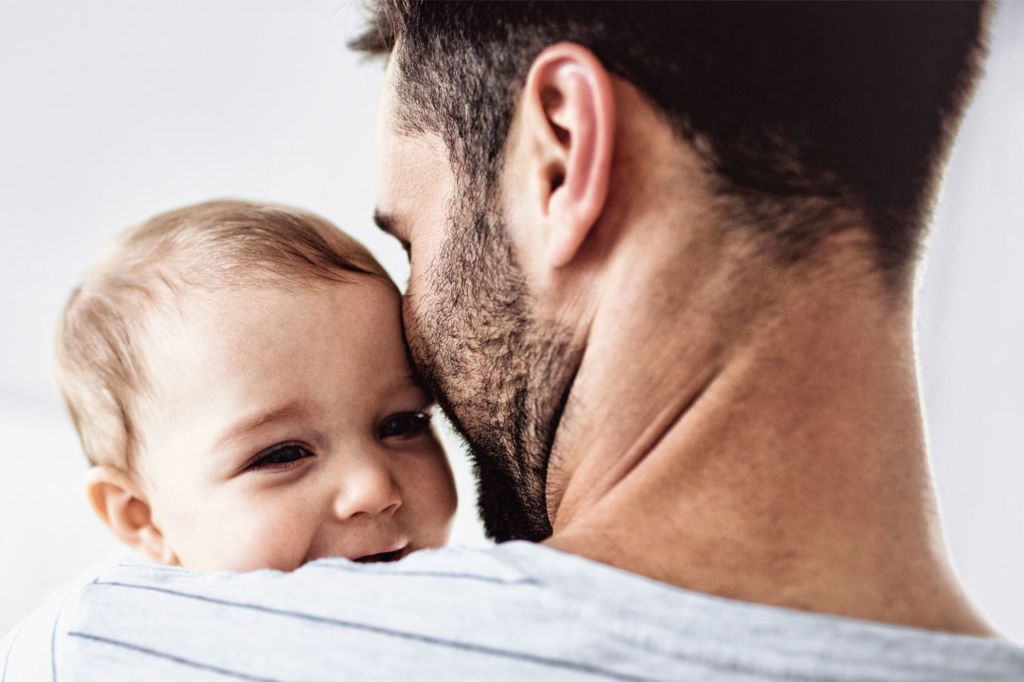 Nahaufnahme eines Vaters, der sein Baby in den Armen hält.