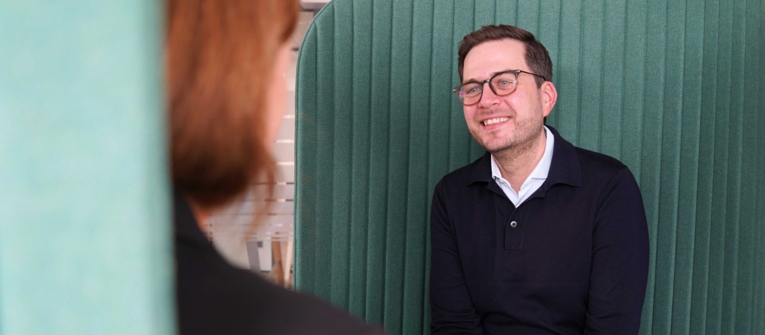 Ein Mann in einer Büroumgebung in einer Interviewsituation.