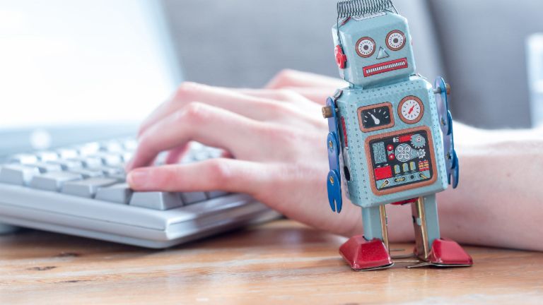 Robotic Process Automation: eine Roboterfigur vor einem Computer.