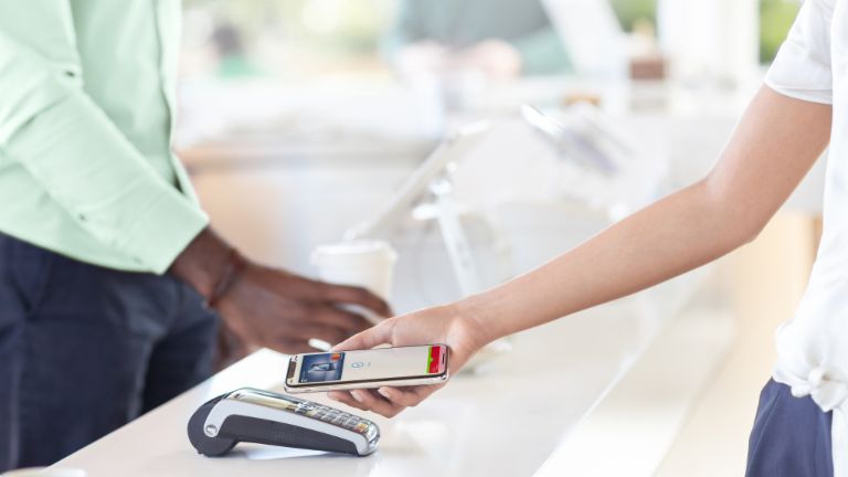 Mobile Payment: Frau bezahlt im Laden per Smartphone.